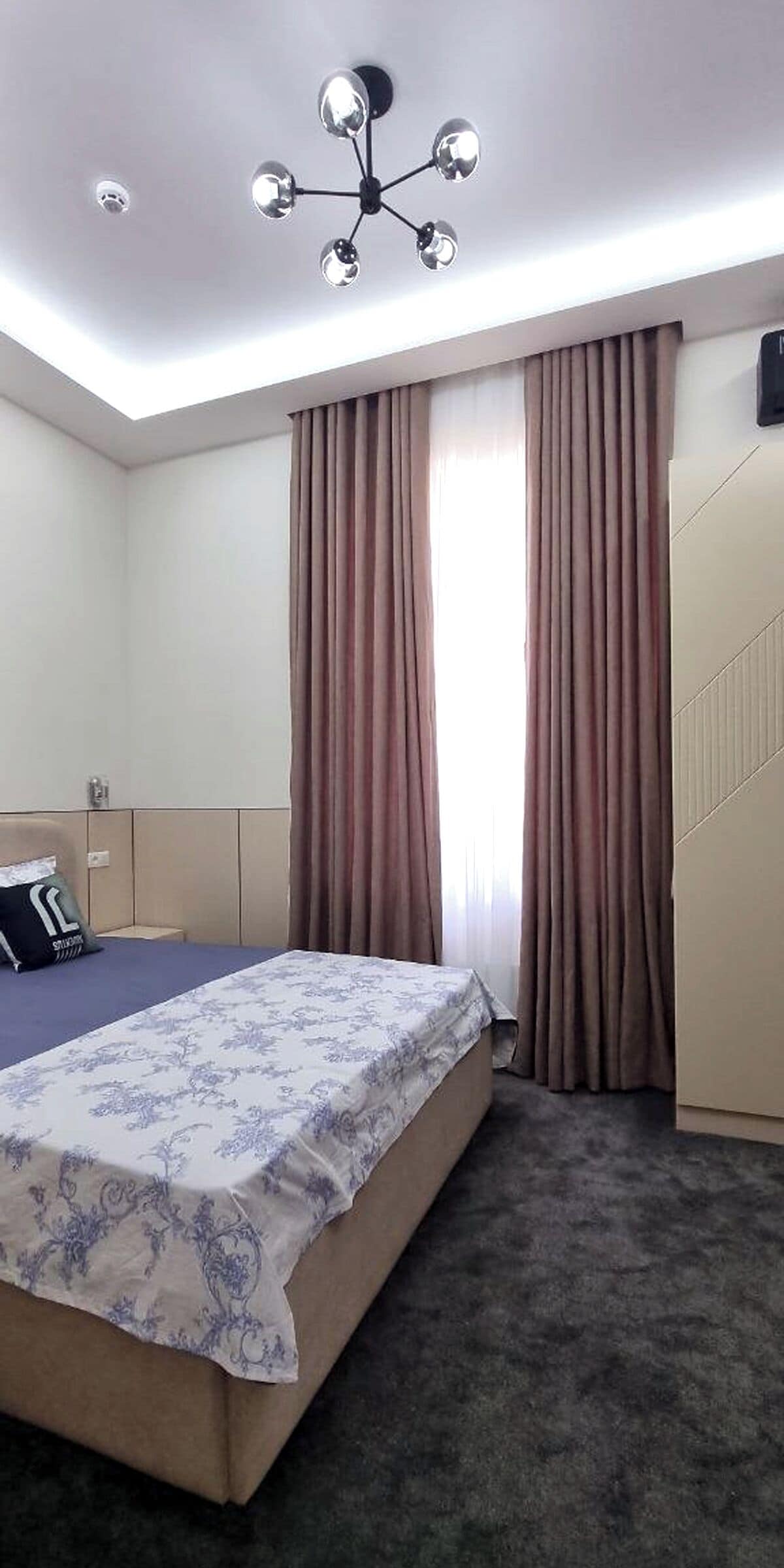 Una habitación de hotel con cama, armario, espejo y lámpara en el techo.