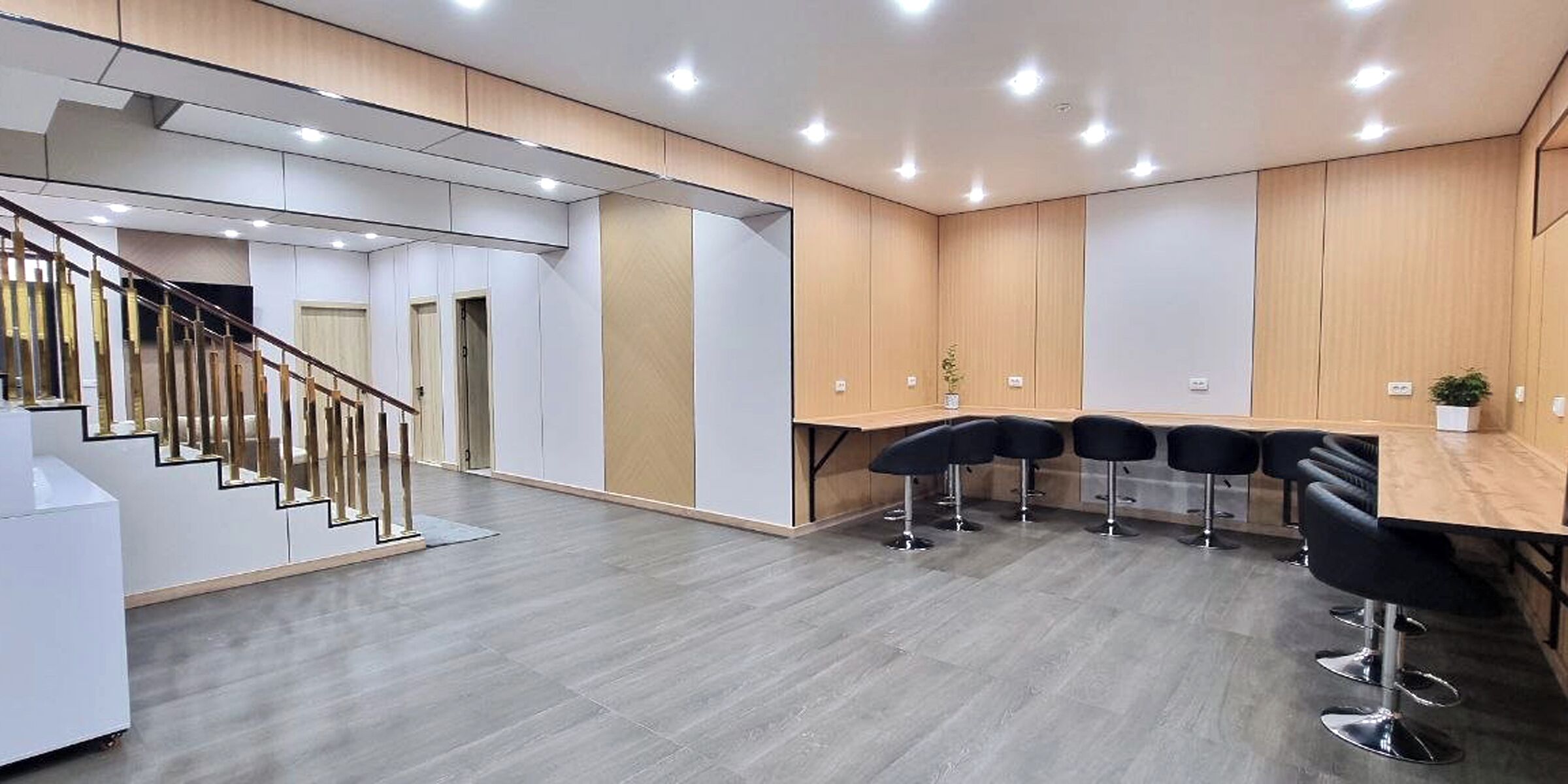 A modern office space with a staircase, a long table with chairs, and a plant on the wall.
