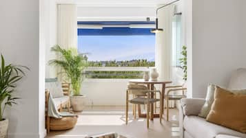 Una sala de estar moderna con balcón, un sofá, una mesa de comedor y una planta en maceta.