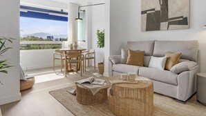 A modern living room with a sofa, a round coffee table, and a dining area with chairs. - Medina Garden 342 in Puerto Ban s - Marbella (Marbella)
