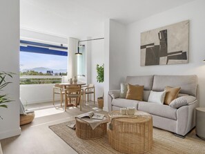 Ein modernes Wohnzimmer mit einer Couch, einem runden Couchtisch und einem Essbereich mit Stühlen.