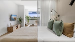 A modern bedroom with a large bed, a TV mounted on the wall, and a view of the outdoors through a sliding door. - Medina Garden 342 in Puerto Ban s - Marbella (Marbella)