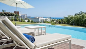 Uma área na piscina com espreguiçadeira, mesa e guarda-sol.