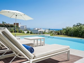 Ein Poolbereich mit Liege, Tisch und Sonnenschirm.