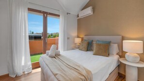 Ein Hotelzimmer mit Bett, zwei Nachttischlampen, einem Fenster mit Vorhängen und einer Klimaanlage.