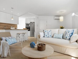 Ein modernes Wohnzimmer mit einer Couch, einem runden Couchtisch und einem Korbstuhl.