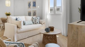 A modern living room with a sofa, a round coffee table, and a television on a wooden stand. - 1 Bdr Playa Roc o 2 (Marbella)