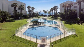 A pool area with a geometric design, surrounded by palm trees and a clear sky. - 1 Bdr Playa Roc o 2 (Marbella)
