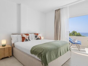 A bedroom with a bed, bedside table, and a view of the sea. - Andalucia del Mar 14 61 (Marbella)