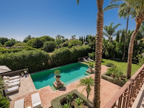 Ein Pool mit klarem, blauem Wasser, umgeben von Palmen und einem gepflegten Garten.