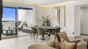 Ein modernes Wohnzimmer mit Essbereich, einer Couch und Meerblick.