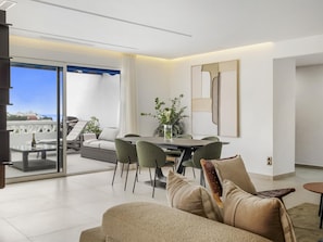 Ein modernes Wohnzimmer mit Essbereich, einer Couch und Meerblick.