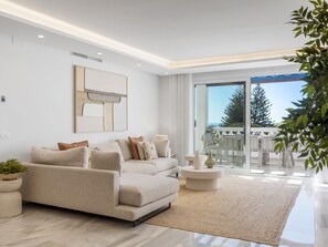 A modern living room with a sofa, a coffee table, and a view of the outdoors. - Casa Granada 2 44 in Puerto Ban s - Marbella (Marbella)