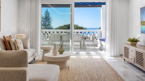 Ein modernes Wohnzimmer mit einer Couch, einem Couchtisch und Blick auf den Balkon.