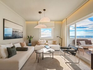 Ein modernes Wohnzimmer mit einer Couch, einem Couchtisch und Meerblick durch große Fenster.
