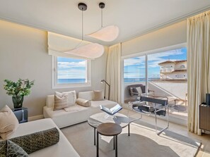 Ein modernes Wohnzimmer mit Sofa, Couchtisch und Blick aufs Meer.