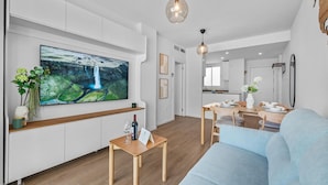 A modern living room with a flat-screen TV, wooden furniture, and a dining area. - Golden Retreat at Puerto Banus (Marbella)