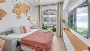 A modern hotel room with a bed, a world map on the wall, a balcony with a view, and a large window with artwork. - Golden Retreat at Puerto Banus (Marbella)