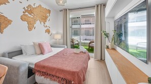 A modern hotel room with a bed, a world map on the wall, a balcony with a view, and a large window with artwork. - Golden Retreat at Puerto Banus (Marbella)