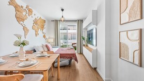 A modern hotel room with a dining area, a world map wall, a large window, and artwork. - Golden Retreat at Puerto Banus (Marbella)