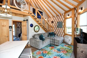 Ein gemütliches Interieur mit einer Holztreppe, einem grauen Sofa und einem kleinen Tisch.