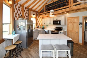 Una cocina con una isla central, vigas de madera, un refrigerador, un microondas y una estufa.