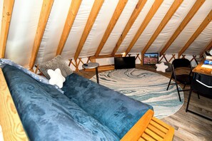 Ein Dachzimmer mit einer Couch, einem kleinen Tisch und einem Stuhl.