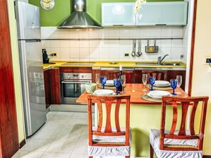 Eine moderne Küche mit Essbereich, ausgestattet mit einem Edelstahl-Kühlschrank, einem eingebauten Backofen und einer gelben Arbeitsplatte.