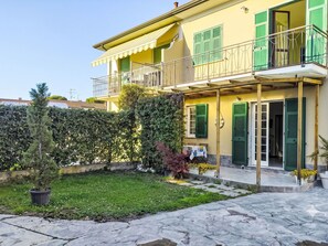 Ein zweistöckiges Gebäude mit Balkon, kleinem Garten und gepflastertem Eingang.