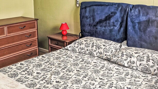 Ein Schlafzimmer mit Bett, Schminktisch, Nachttisch und Lampe.