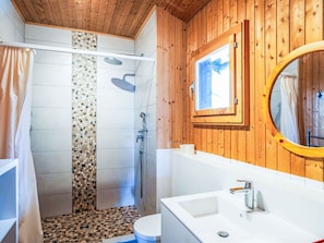 Ein Badezimmer in einer Holzhütte mit Dusche, Toilette und Waschbecken.