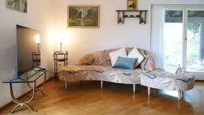Un soggiorno con un divano, una televisione, una lampada e un quadro appeso al muro.