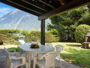 Ein Essbereich im Freien mit einem Tisch für zwei Personen, umgeben von Stühlen und mit Blick auf eine Berglandschaft.