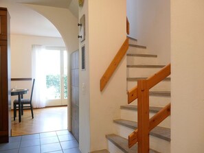 Eine Treppe mit Holzhandläufen und Fliesenboden, die zu einem Raum mit Tür und Fenster führt.