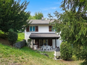 Ein zweistöckiges Haus mit Terrasse und kleinem Garten.