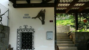 Un ingresso di un edificio con un cancello in metallo, un cartello di legno sopra il cancello, un muro in pietra e una scala che sale.