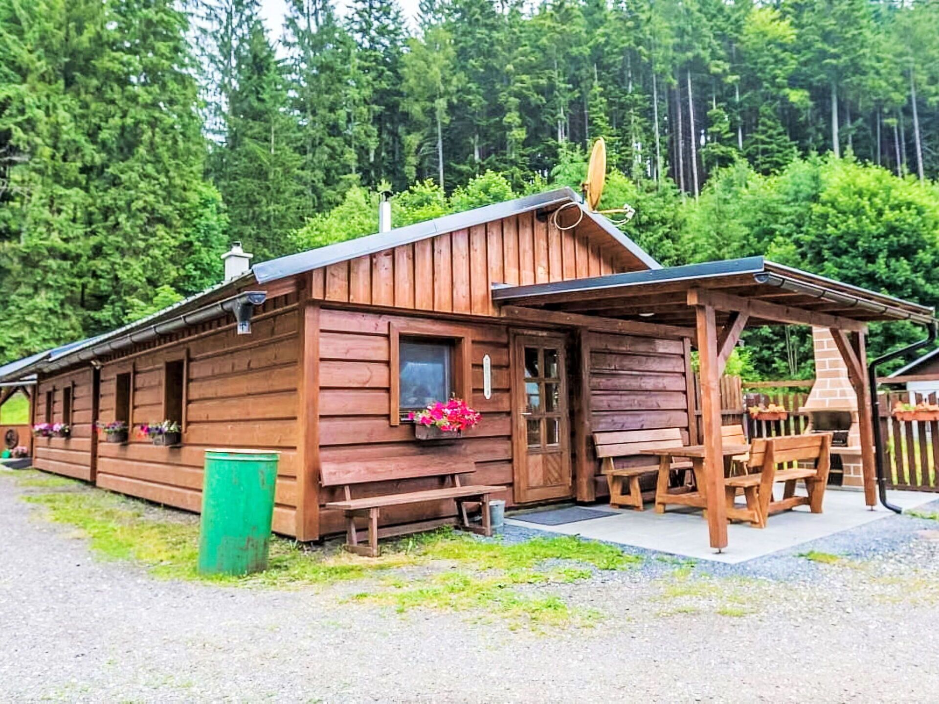 A wooden cabin with a porch, a bench, and a small table.