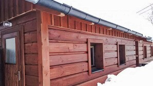 A wooden cabin with a sloped roof and multiple windows.