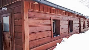 A wooden cabin with a sloped roof and multiple windows.