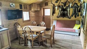 Un intérieur en bois comprenant une table à manger, des chaises, un canapé et des crânes d’animaux fixés au mur.