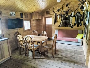 Un interior de madera con una mesa de comedor, sillas, un sofá y cráneos de animales montados en la pared.