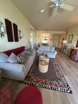 A living room with a sofa, two side tables, a patterned rug, and a ceiling fan. - Sun Worshipper Cozy Condo Retreat (Fort Meyers)