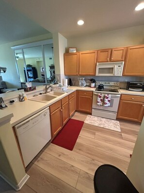 Une cuisine moderne avec des meubles en bois, un lave-vaisselle, un four à micro-ondes, une cuisinière et un tapis rouge.