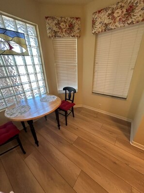 A dining area with a round table, two chairs, and a window with blinds. - Sun Worshipper Cozy Condo Retreat (Fort Meyers)