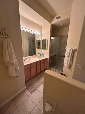 Un bagno con doppio lavabo, doccia e servizi igienici.