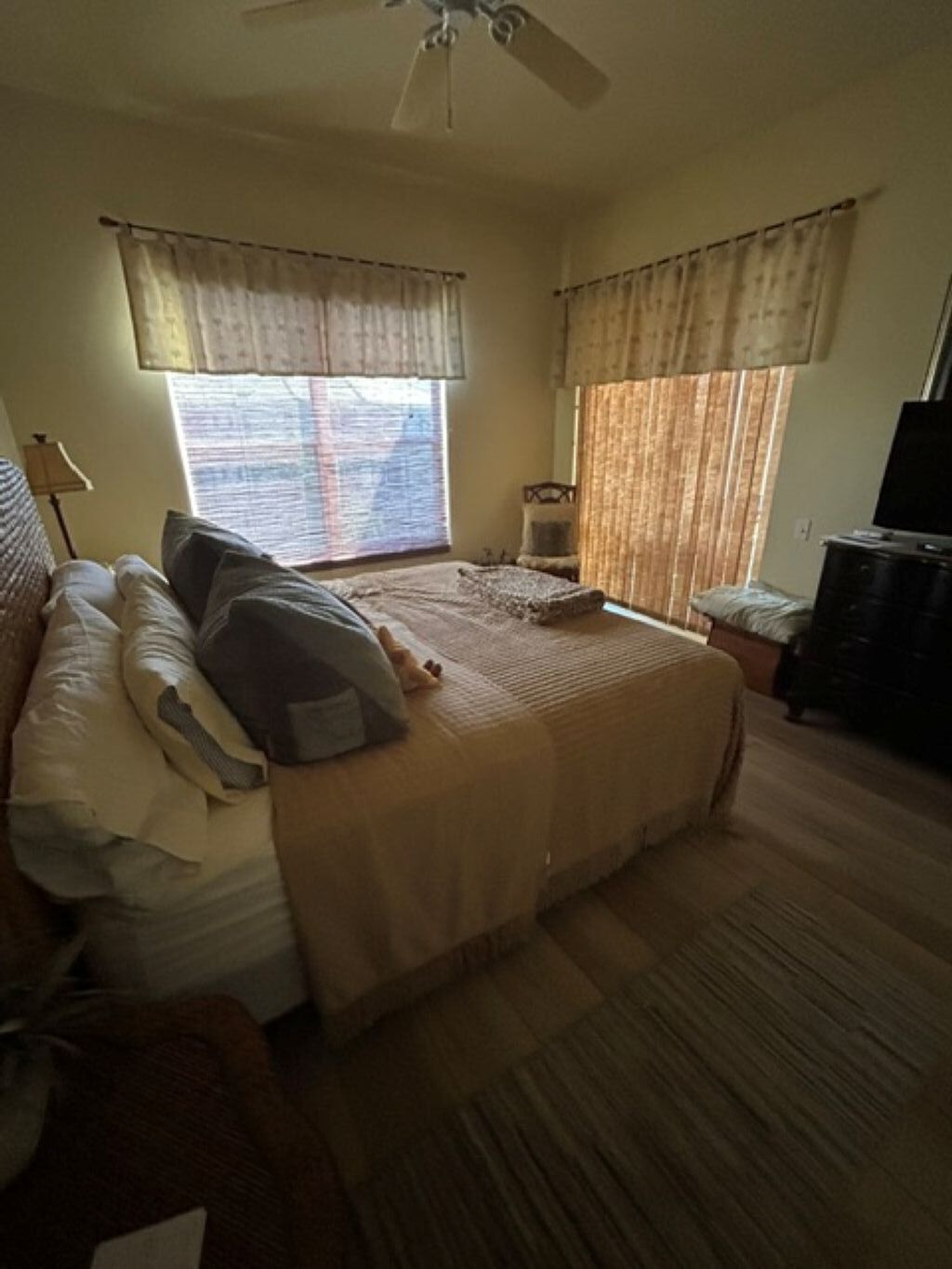 Um quarto com uma cama, uma cadeira, uma escrivaninha e uma televisão.