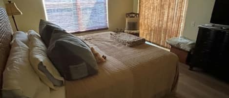 Um quarto com uma cama, uma cadeira, uma escrivaninha e uma televisão.