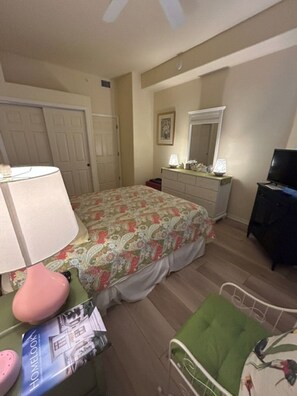 A bedroom with a bed, dresser, mirror, television, and a green chair. - Sun Worshipper Cozy Condo Retreat (Fort Meyers)