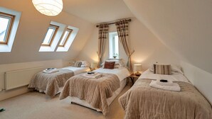 Ein Schlafzimmer mit zwei Betten, einem Dachfenster und einer Pendelleuchte.