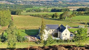 Ein Landhaus mit Solaranlage, umgeben von grünen Feldern und einem entfernten Dorf.